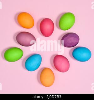 Creative arrangement with colorful vibrant natural eggs on pastel pink background. Flat lay Easter concept Stock Photo