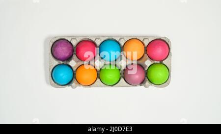 Colorful Easter eggs in card box on white background. Flat lay Stock Photo