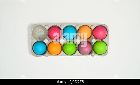 Colorful Easter eggs in card box on white background. Flat lay Stock Photo