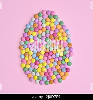 Creative Easter egg made with colorful candies on pastel pink background. Flat lay Easter concept Stock Photo