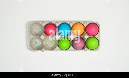 Colorful Easter eggs in card box on white background. Flat lay Stock Photo
