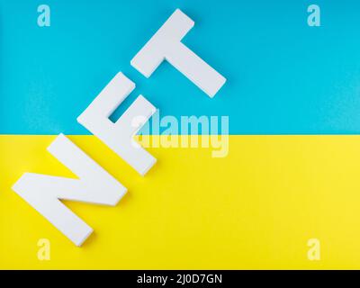 NFT inscription with white 3d letters on a blue-yellow background. Non-fungible token against background of colors of the Ukrainian flag. Crypto art c Stock Photo