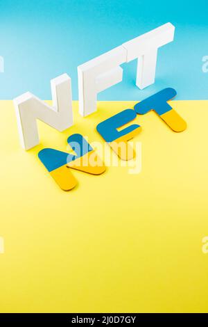 NFT inscription with white 3d letters on a blue-yellow background. Non-fungible token against background of colors of the Ukrainian flag. Crypto art c Stock Photo