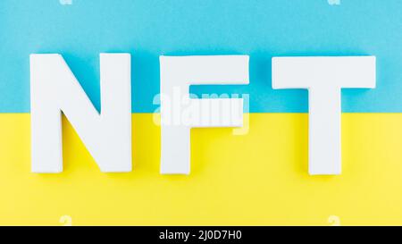 NFT inscription with white 3d letters on a blue-yellow background. Non-fungible token against background of colors of the Ukrainian flag. Crypto art c Stock Photo