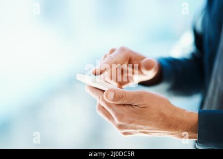 Connected at the touch of a button. Cropped shot of an unrecognizable businessman sending a text message. Stock Photo