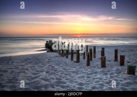 Ruins of the old Naples Pier at sunset on the ocean Stock Photo