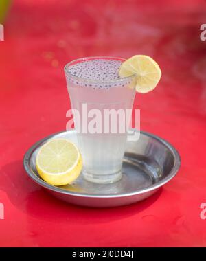 Glass of lime water or lemonade on a wet red  plastic top Stock Photo