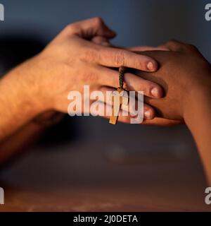 Finding comfort in religion. Closeup shot of a two people holding hands in support with a rosary. Stock Photo