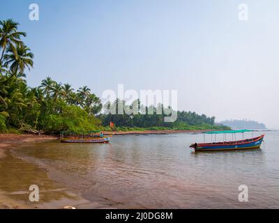 Sindhudurg, India - December  21, 2021 : Beautiful landscape of the Arabian sea with coconut trees and fishing boat Stock Photo