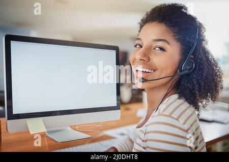 Staying connected is what keeps my business thriving. Portrait of a young woman wearing a headset while working on a computer at home. Stock Photo