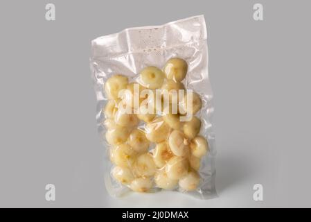 Small flat onions (in Italy called borettane onions) in vacuum packed sealed for sous vide cooking isolated on Gray background Stock Photo
