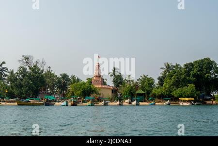 Sindhudurg, INDIA - December 23, 2021 : Beautiful landscape of the Indian ocean with coconut trees, fishing boats and temple at Sindhudurg district Stock Photo