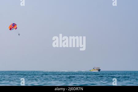 Sindhudurg, INDIA - December 23, 2021 : Unidentified tourist enjoying a parasailing ride at Tarkarli beach. The beach is famous for various water spor Stock Photo