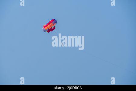 Sindhudurg, INDIA - December 23, 2021 : Unidentified tourist enjoying a parasailing ride at Tarkarli beach. The beach is famous for various water spor Stock Photo