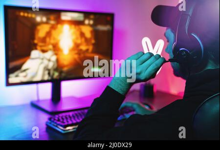 Young gamer playing video games online First-Person Shooter while broadcasting on social media - Working live streaming on internet platforms Stock Photo