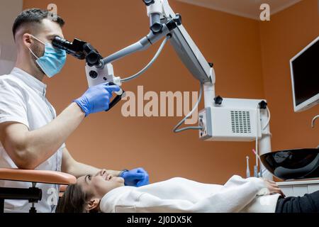 Dentist looking through a microscope at the patient's teeth. Modern progressive dentistry. Stock Photo
