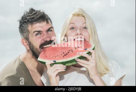 Watermelon as a symbol of summer, unity and oneness. Portrait of happy couple enjoying watermelon on summer holiday, having fun together. Stock Photo