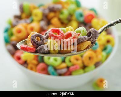 Macro shot. Crispy cereal rings in different colors on a spoon and in a bowl. Quick whole grain breakfast, healthy nutrition. Healthy lifestyle. Child Stock Photo