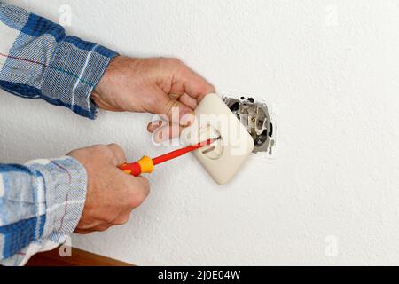 Worker is mounting an electrical socket into a wall Stock Photo