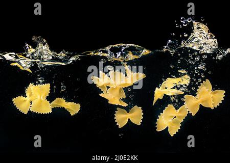 butterflies pasta falling in the boiling water on dark background. Underwater view. Cooking, cooking at home, italian cuisine concept Stock Photo
