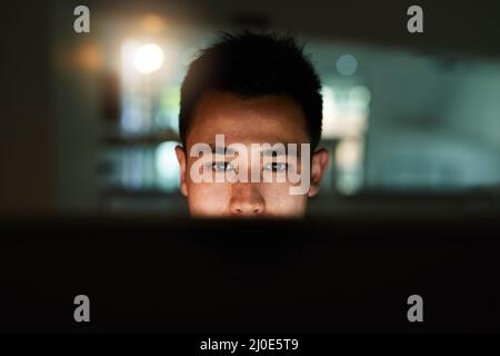 Late night work session. Shot of a handsome young male programmer working late in his office. Stock Photo