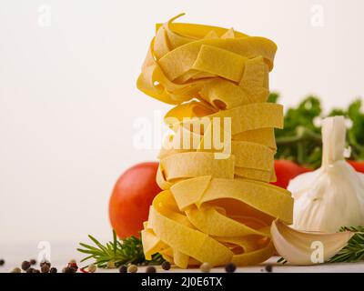 Italian Cuisine. Pasta in an interesting vertical serving, fresh vegetables, herbs on a white background. Italian cuisine dishes, recipes, cooking, re