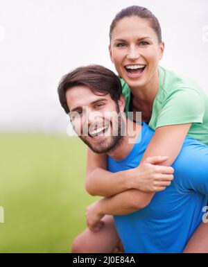 Even working out is fun when were together. Shot of a young man playfully carrying his girlfriend on his back while working out. Stock Photo