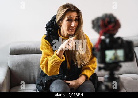 Young attractive woman blogger or vlogger looking and pointing at camera and talking on video shooting with technology. Social media influencer people Stock Photo