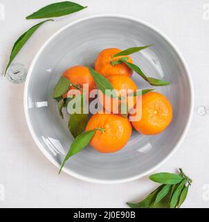 Tangerines with green leaves on white wooden background. Close up Stock Photo