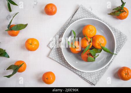 Tangerines on white wooden background. Grey polka dot fabric Stock Photo
