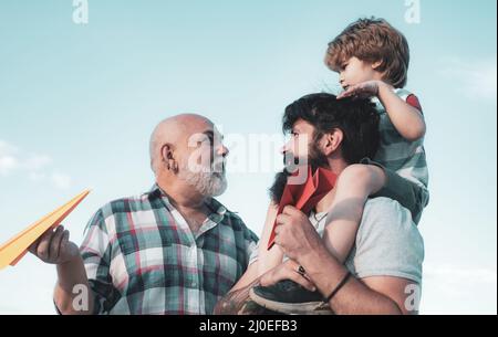 Family people. Airplane ready to fly. Male multi generation family. Kid pilot with toy jetpack against sky background. Happy fathers day. Stock Photo
