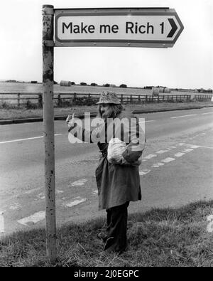 A picture from a series of humurous novelty images taken by Sunday People photographer Dennis Hutchinson. - Well, who knows, this could be his lucky day. 'Make Me Rich' sign Stock Photo