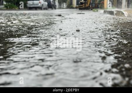 Rain drops falling on city street Stock Photo