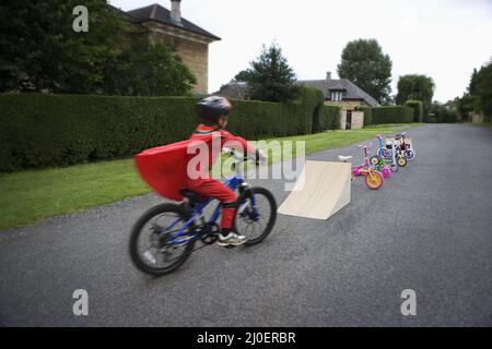 Young boy riding bicycle towards ramp
