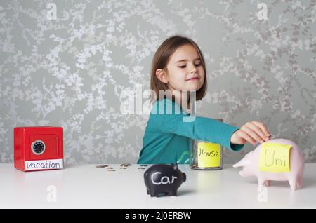 Girl holding a coin surround by piggy banks and money boxes Stock Photo ...