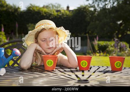 Pre teen caucasian girl watering flower pots in a garden Stock Photo