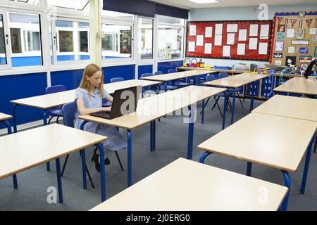 Primary school caucasian girl using a laptop in an empty classroom Stock Photo