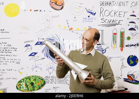 Middle aged caucasian rocket scientist standing in front of astronomy drawings on wall department of Stock Photo