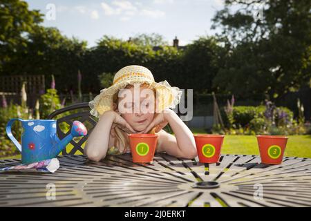 Pre teen caucasian girl watering flower pots in a garden Stock Photo
