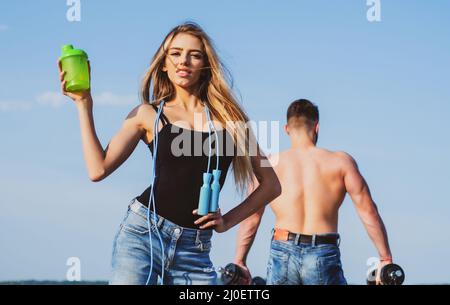 https://l450v.alamy.com/450v/2j0ettg/slim-woman-fitness-trainer-with-protein-shaker-smiling-young-female-and-personal-couple-coach-man-and-girl-with-protein-shake-bottle-and-skipping-2j0ettg.jpg