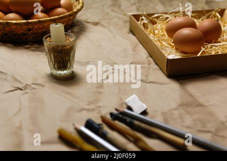 Rustic background. Tools for decorating Paschal eggs, Pysankas, with wax-resist dyeing technique. Collection of eggs. Homemade pen and melted beeswax Stock Photo