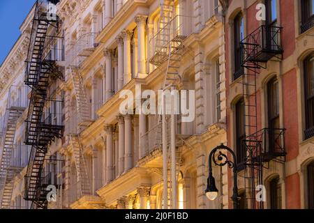 Facades of Soho loft buildings with fire escapes at dusk. Lower Manhattan, New York City Stock Photo