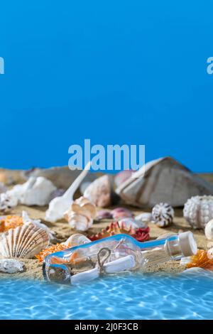 A glass bottle with a letter washed up on the beach shore. Sea beach full of shells and sand. Blue sky. Clean water. Stock Photo