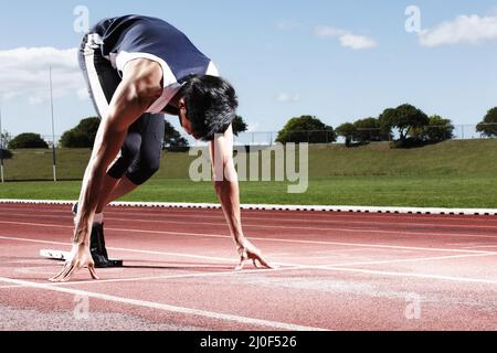 Ready to win this race. A young runner at the starting line. Stock Photo