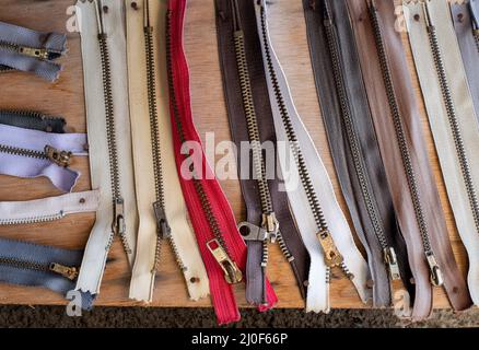 Worn used cloth zippers  on a wooden board Stock Photo