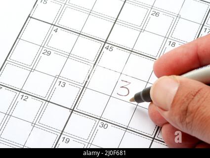 Hand Solving a Crossword Puzzle. Mind games Stock Photo