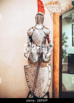 Russia, Sochi 14.03.2020. The figure of a medieval knight in a helmet with a feather armor with a sword and shield stands in the Stock Photo