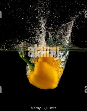 Yellow bell pepper dropped and slashing on water Stock Photo