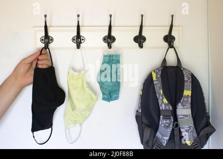 A person about to get a face mask form a Wall Hook or Coat Rack on a white wall Stock Photo