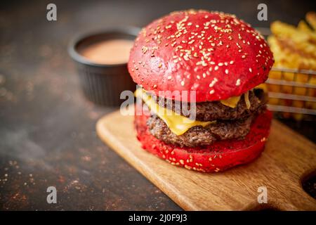 Homemade red sesame bun double bacon cheese burger. Served with french fries on wooden board. Stock Photo